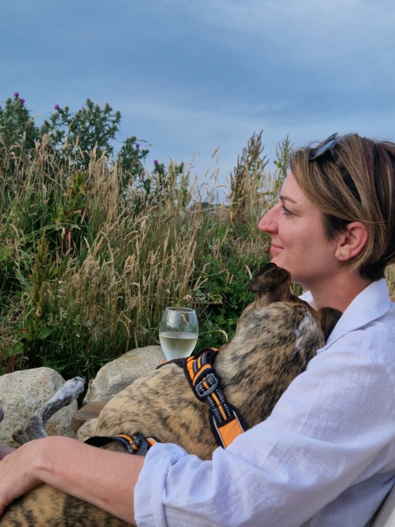 dog on lady knee drinking wine
